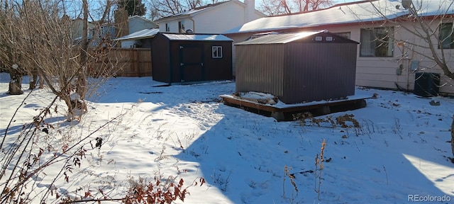 snowy yard featuring central air condition unit and a storage shed