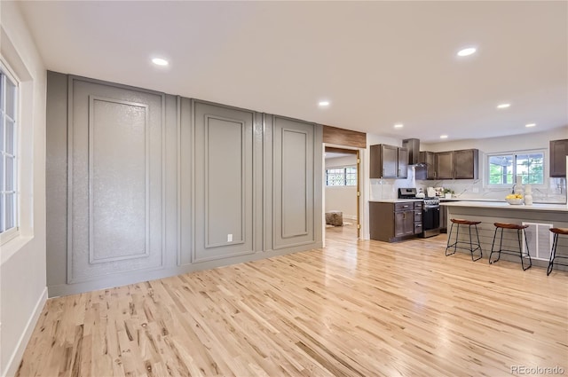 5720 E Caley Ave, Centennial, CO 80111 - kitchen featuring electric range, a kitchen bar, light wood-style flooring, wall chimney range hood, and backsplash