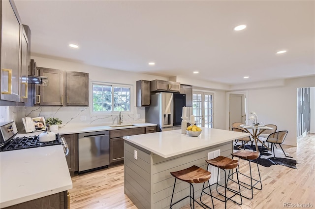 5720 E Caley Ave, Centennial, CO 80111 - kitchen with appliances with stainless steel finishes, a kitchen bar, light wood-style floors, light countertops, and tasteful backsplash