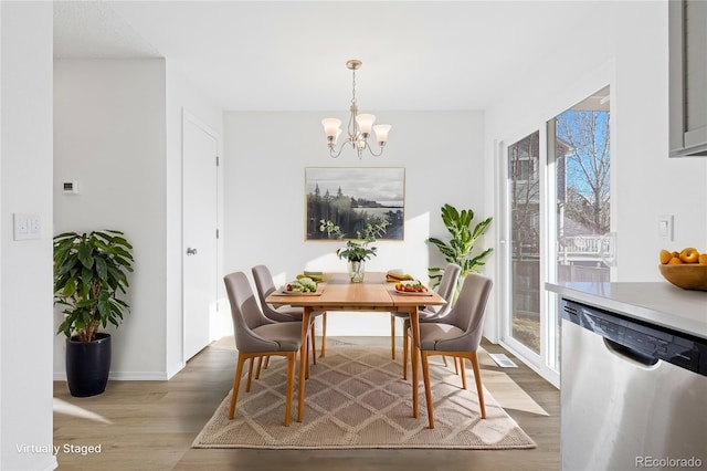 dining space featuring a chandelier, baseboards, and wood finished floors