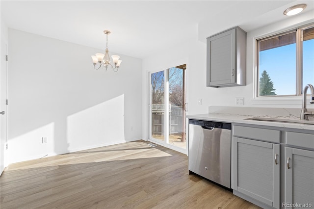 kitchen with decorative light fixtures, gray cabinets, stainless steel dishwasher, light wood-style floors, and a sink