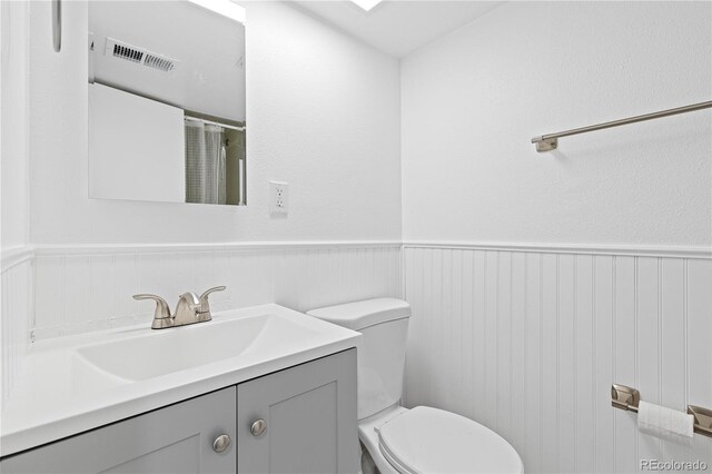 bathroom with wainscoting, visible vents, vanity, and toilet