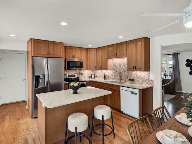 6943 Ingalls St, Arvada, CO 80003 - kitchen featuring appliances with stainless steel finishes, a sink, light wood-type flooring, tasteful backsplash, and recessed lighting