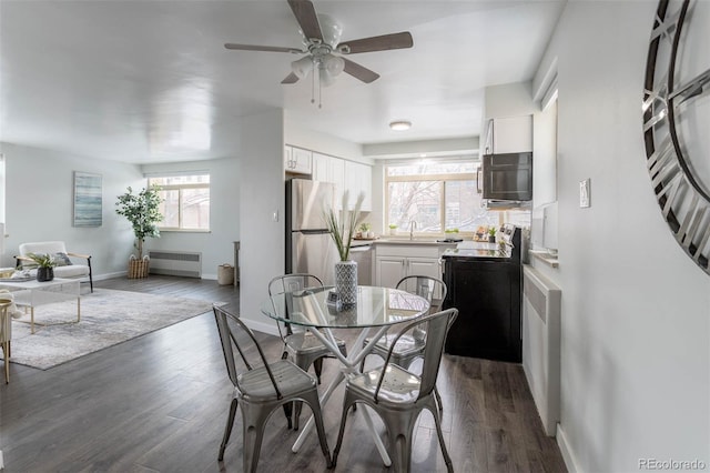 dining room with radiator heating unit, ceiling fan, sink, and dark hardwood / wood-style floors