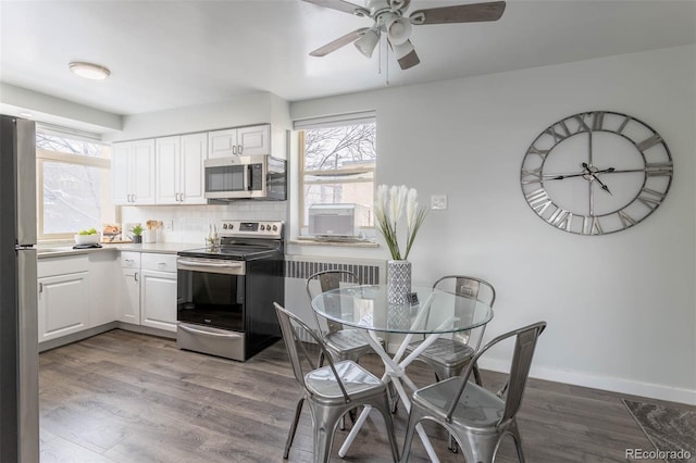 kitchen featuring hardwood / wood-style flooring, stainless steel appliances, and white cabinetry