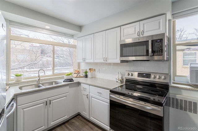 kitchen featuring appliances with stainless steel finishes, decorative backsplash, sink, and white cabinetry