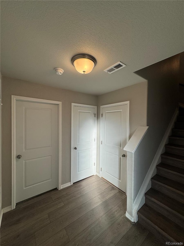 corridor featuring a textured ceiling and dark hardwood / wood-style floors