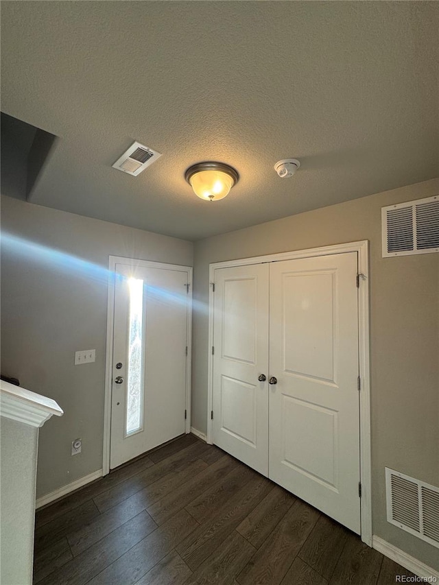 foyer with dark hardwood / wood-style flooring and a textured ceiling