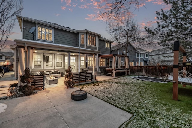 back house at dusk with a yard, a patio, and an outdoor living space with a fire pit