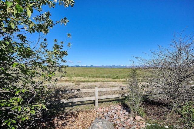 view of yard with a rural view, fence, and a mountain view