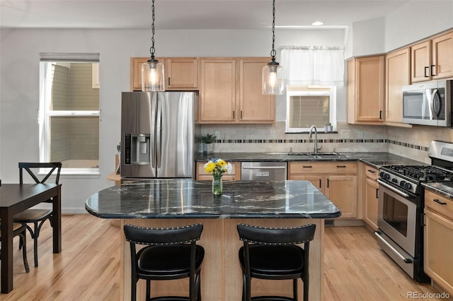 3670 Wolff St, Denver, CO 80212 - kitchen featuring appliances with stainless steel finishes, light brown cabinets, backsplash, light wood-style floors, and a kitchen breakfast bar