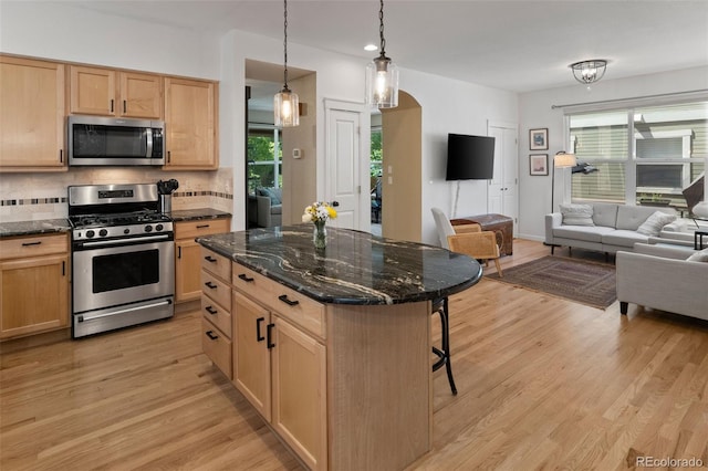3670 Wolff St, Denver, CO 80212 - kitchen with stainless steel appliances, open floor plan, arched walkways, a kitchen bar, and light brown cabinets