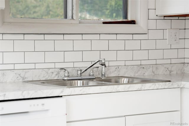 kitchen featuring white cabinets, white dishwasher, backsplash, and sink