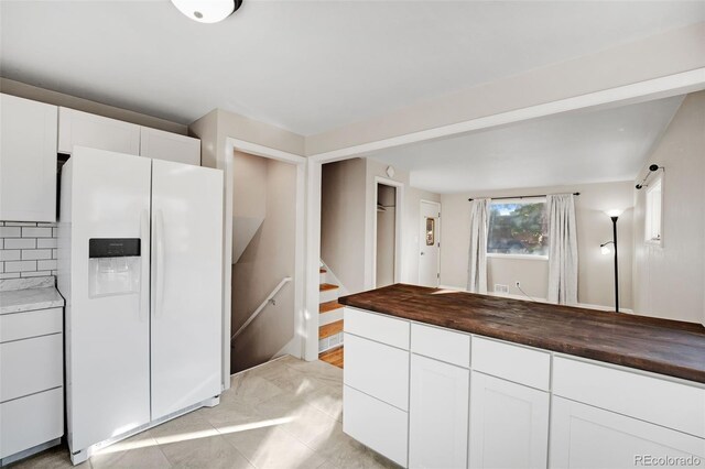 kitchen with white cabinets, light tile patterned floors, tasteful backsplash, butcher block countertops, and white fridge with ice dispenser