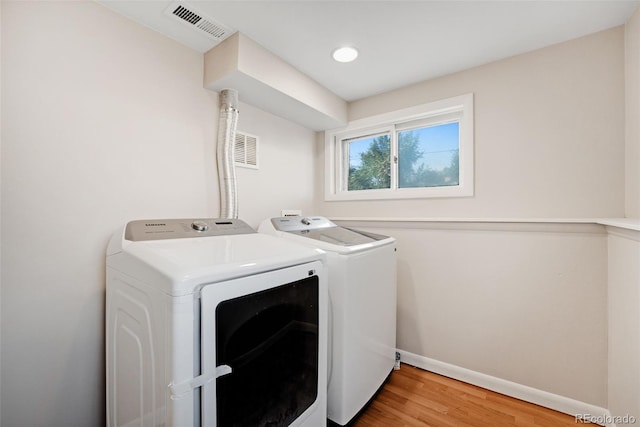 clothes washing area featuring wood-type flooring and separate washer and dryer