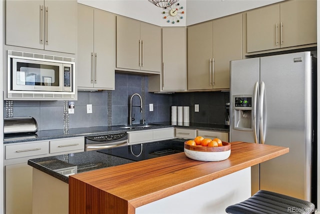 kitchen with gray cabinets, a sink, a kitchen breakfast bar, appliances with stainless steel finishes, and decorative backsplash