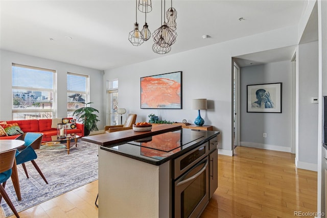 kitchen with pendant lighting, a center island, oven, and light wood-style floors