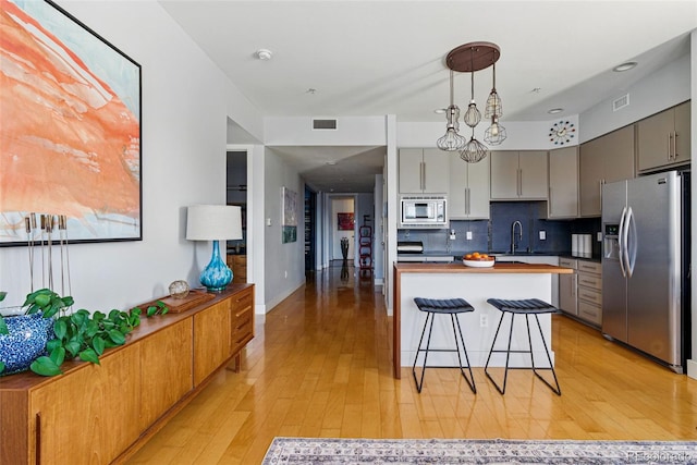 kitchen with visible vents, a breakfast bar, gray cabinets, a sink, and appliances with stainless steel finishes