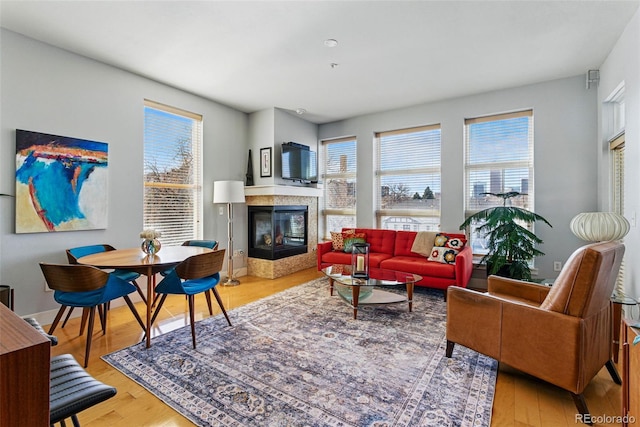 living room featuring a multi sided fireplace, a healthy amount of sunlight, and wood finished floors