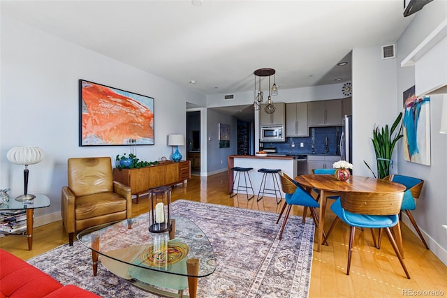 living room with visible vents, baseboards, and light wood-style flooring