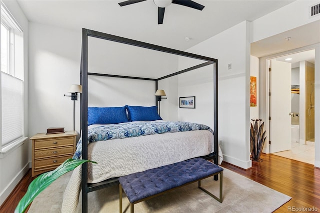 bedroom with a ceiling fan, wood finished floors, visible vents, and baseboards