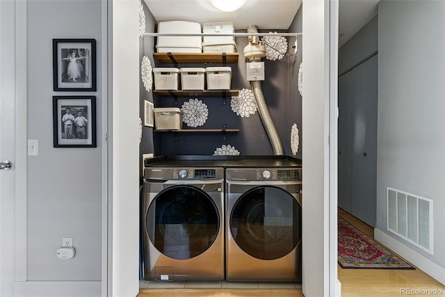 clothes washing area with visible vents, independent washer and dryer, and wood finished floors