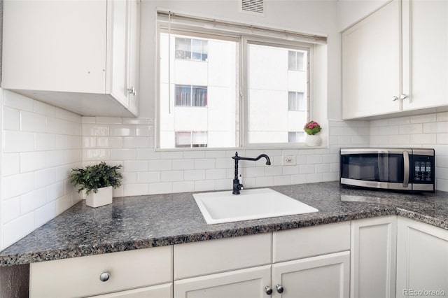 kitchen featuring backsplash, sink, and white cabinetry