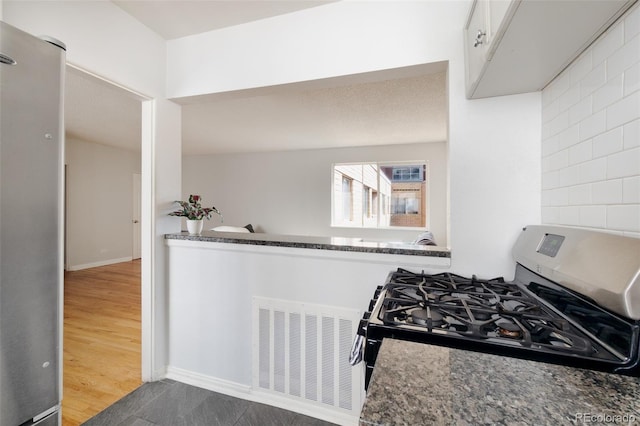 kitchen featuring hardwood / wood-style flooring, dark stone counters, and gas stove