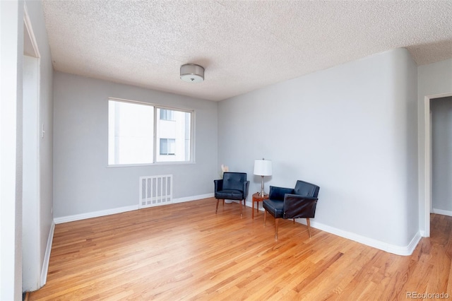 living area with a textured ceiling and light hardwood / wood-style flooring