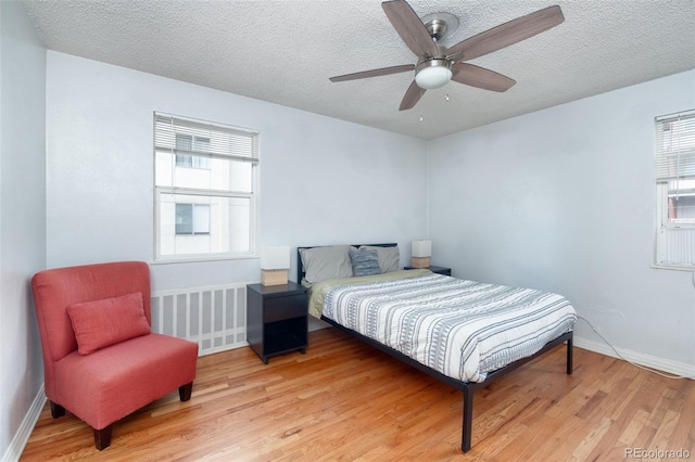 bedroom with ceiling fan, radiator, a textured ceiling, and light wood-type flooring