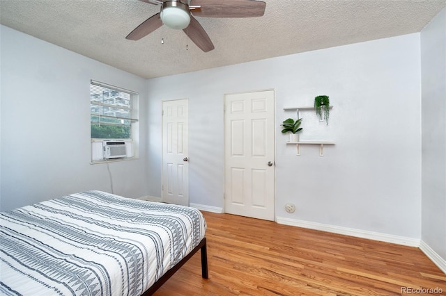 bedroom with wood-type flooring, cooling unit, a textured ceiling, and ceiling fan