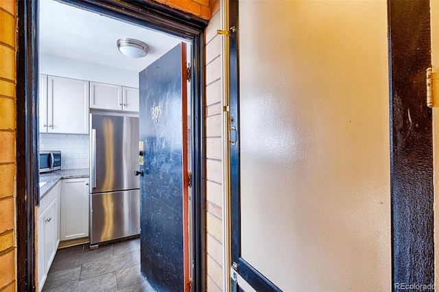 kitchen with decorative backsplash, light stone countertops, white cabinets, and appliances with stainless steel finishes