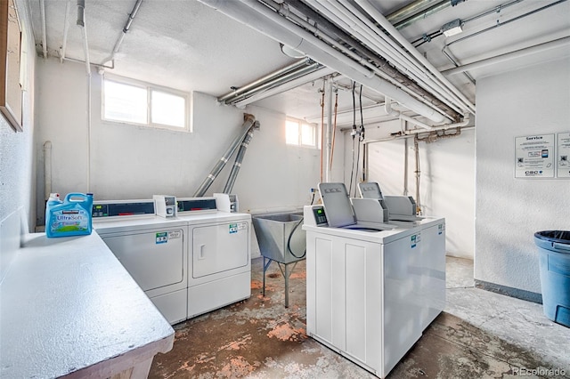 washroom featuring a wealth of natural light, washer and clothes dryer, and sink