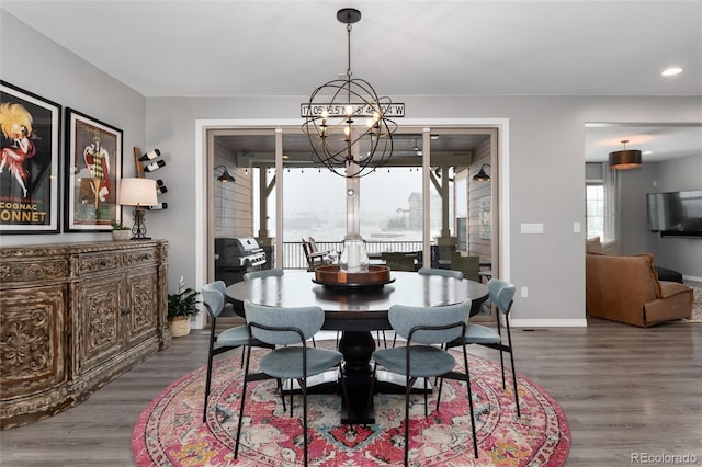 dining space featuring baseboards, recessed lighting, a notable chandelier, and wood finished floors
