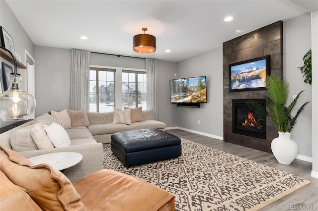 living area with baseboards, recessed lighting, wood finished floors, and a fireplace