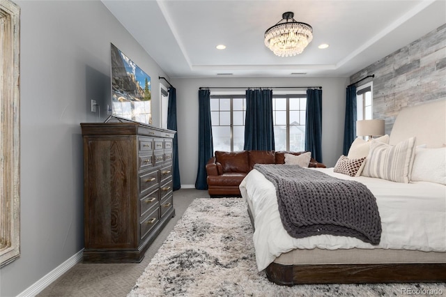 bedroom with a raised ceiling, light colored carpet, baseboards, and a notable chandelier