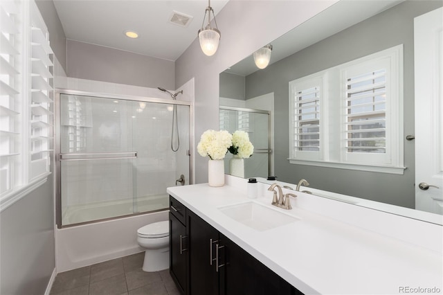 full bathroom with visible vents, bath / shower combo with glass door, toilet, vanity, and tile patterned floors