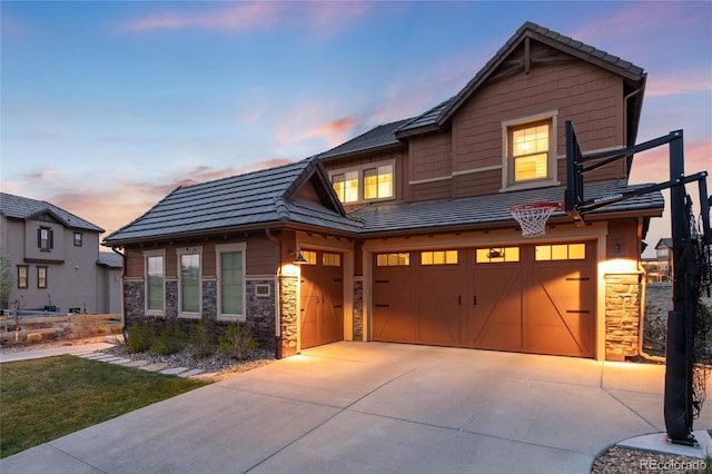 view of front of property featuring a garage, stone siding, a tiled roof, and concrete driveway
