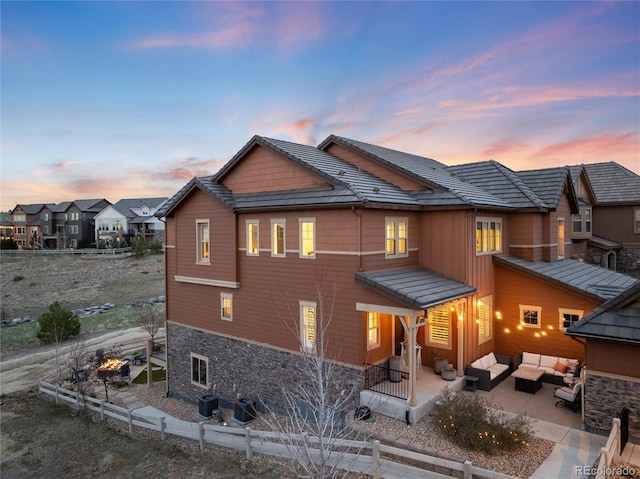 view of front of house featuring stone siding, outdoor lounge area, a residential view, and a patio