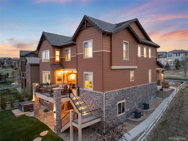 back of house featuring an outdoor hangout area, central air condition unit, stone siding, and a deck