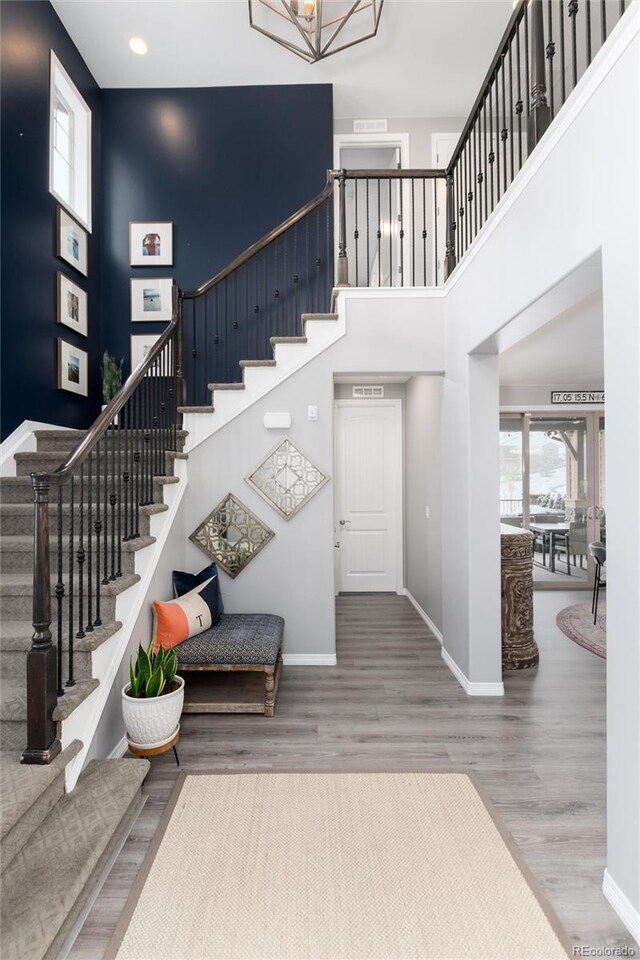 stairway featuring an inviting chandelier, recessed lighting, a high ceiling, wood finished floors, and baseboards