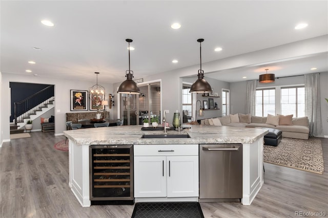kitchen featuring open floor plan, a kitchen island with sink, dishwasher, beverage cooler, and a sink