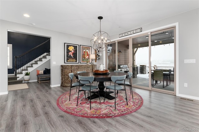 dining space with visible vents, stairway, wood finished floors, baseboards, and a notable chandelier