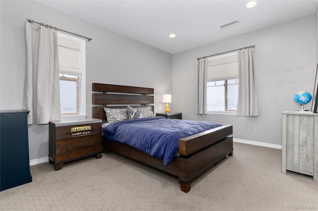 bedroom featuring visible vents, baseboards, multiple windows, and light carpet