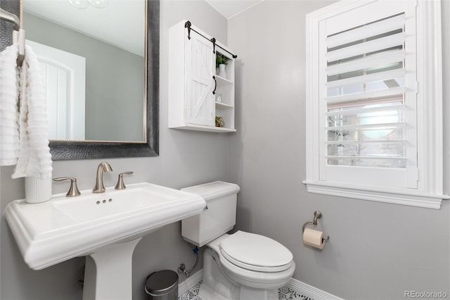 half bathroom featuring toilet, baseboards, and a sink