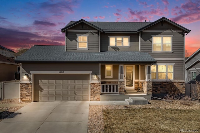 view of front of property featuring stone siding, a porch, driveway, and fence