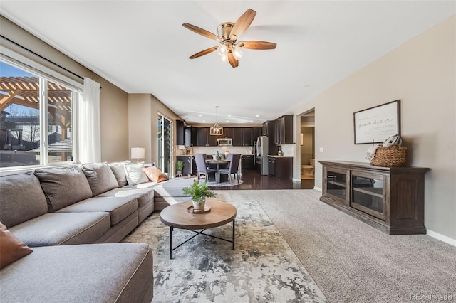 living room with ceiling fan, baseboards, dark carpet, vaulted ceiling, and a glass covered fireplace