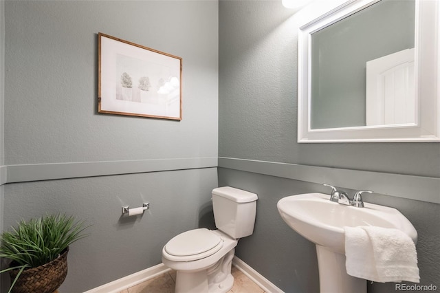 half bathroom featuring tile patterned flooring, toilet, and baseboards