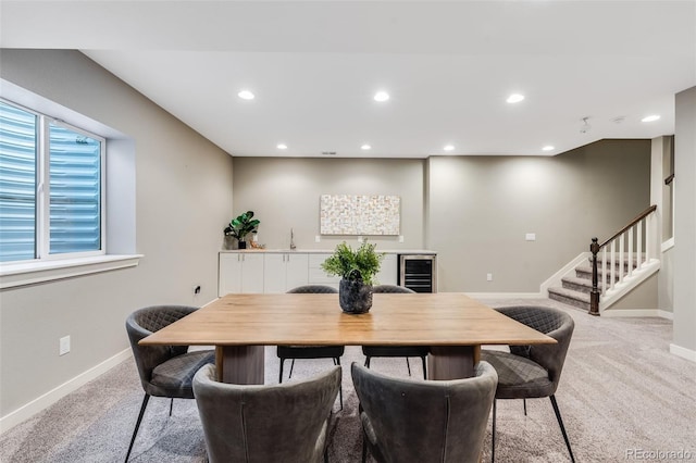 dining area with baseboards, beverage cooler, stairway, light colored carpet, and recessed lighting