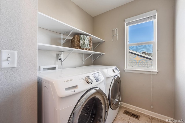 washroom featuring visible vents, washing machine and dryer, light tile patterned floors, baseboards, and laundry area